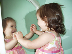 little girl talking to reflection in mirror